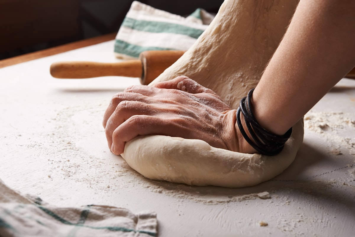 Manos amasando masa de pan sobre una mesa enharinada